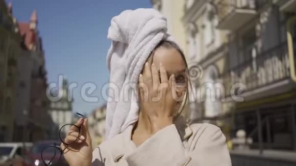 可爱的年轻女子的肖像头上戴着毛巾戴着眼镜站在街上微笑着看着相机视频的预览图