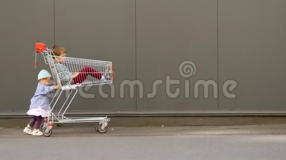 小女孩推着购物车哥哥坐在里面儿童在等待来自视频的预览图