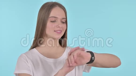 美丽的年轻女性使用智能手表蓝色背景视频的预览图