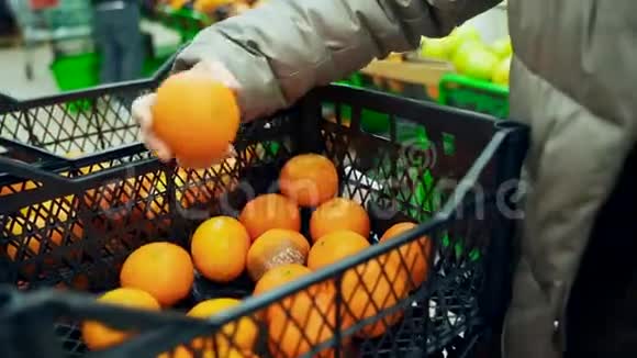 超市里的一个女人从一个盒子里拿出橘子放进一个袋子里把橘子放进抽屉里视频的预览图