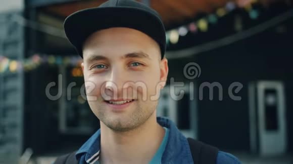 戴着时髦帽子站在户外微笑的年轻人的特写照片视频的预览图