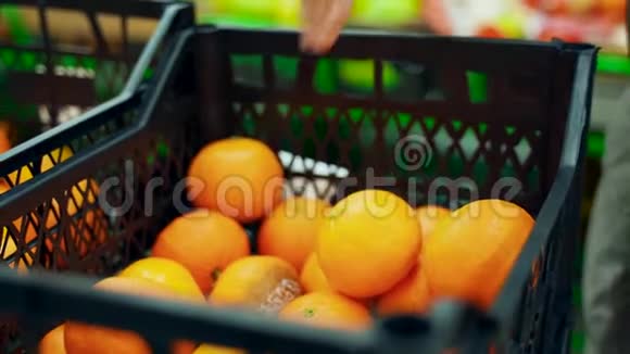 超市里的一个女人从一个盒子里拿出橘子放进一个袋子里视频的预览图