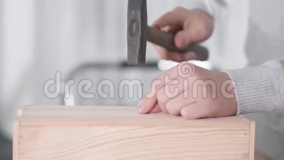 年轻白种人男孩的特写他的手在敲打钉子孩子在做木工木工儿童木工爱好视频的预览图