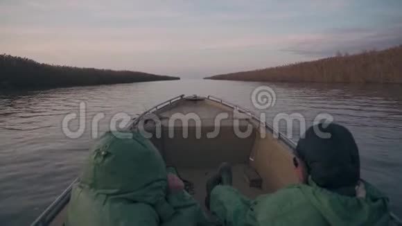 穿着绿色雨衣的钓鱼者乘着船在河上疾驰视频的预览图