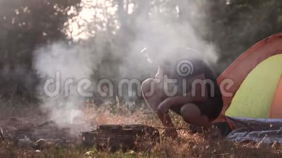 一个年轻人正在森林里的火上烤肉视频的预览图