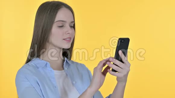 在智能手机黄色背景下庆祝休闲年轻女性视频的预览图