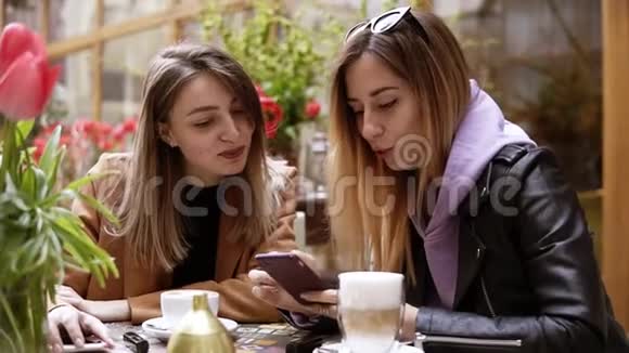 两个穿着休闲服装的头发的年轻女性在街头咖啡店放松和交谈1分享视频的预览图