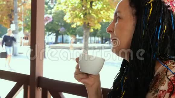 令人印象深刻的高白种人黑发女人在城市街道的街头咖啡馆喝咖啡视频的预览图