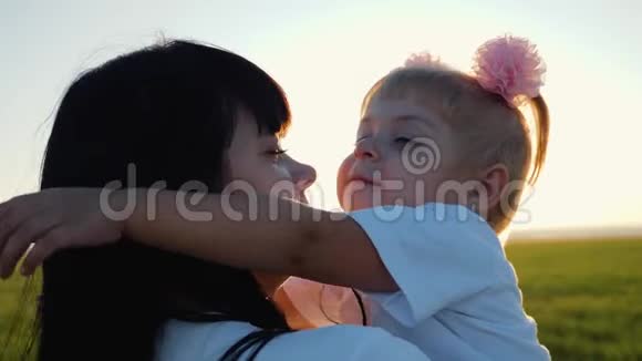 一个幸福的家庭年轻的母亲在夕阳下的田野里拥抱小女儿家庭关系的脆弱性视频的预览图