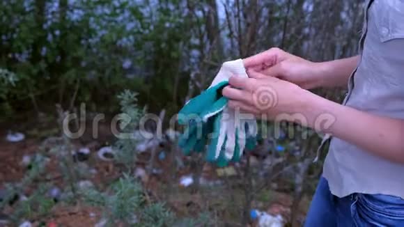 志愿者妇女戴上手套在森林里捡垃圾双手特写视频的预览图