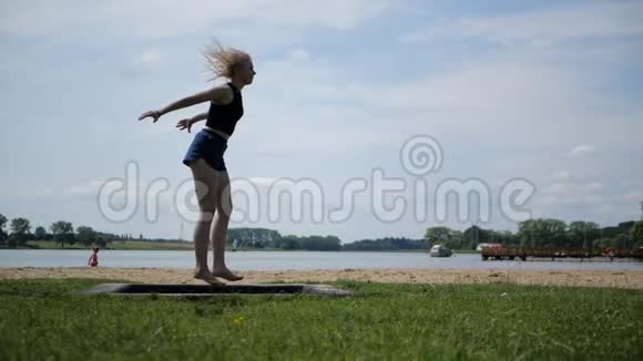 充满活力的快乐女孩金发美女在大自然的蹦床上跳跃视频的预览图