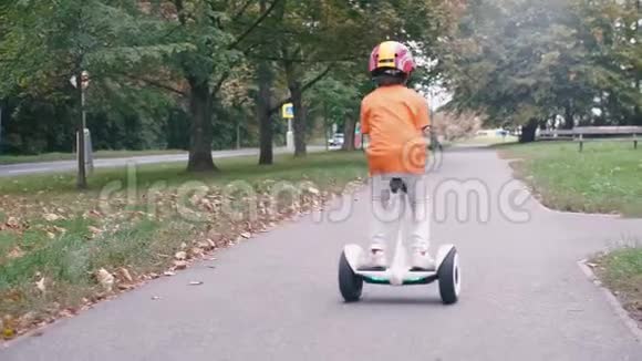男孩骑着陀螺滑板车向前走转过身然后回去视频的预览图