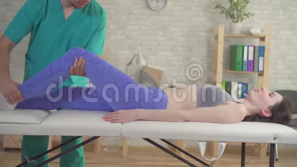 治疗师治疗受伤的膝盖运动员女性病人视频的预览图