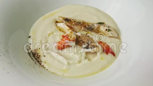特写手拿大汤匙的鱼膏汤上面有对虾和香料视频的预览图
