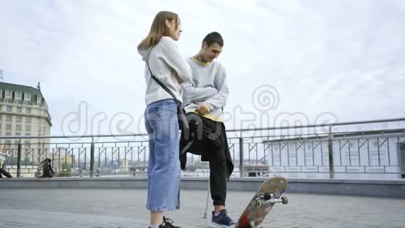 一条腿拄着拐杖滑板的年轻人在街上和他的女朋友聊天残疾人的积极生活视频的预览图