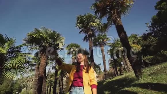 快乐的女孩在美丽的晴天在棕榈树的背景下自拍视频的预览图