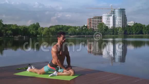 在湖边放松的英俊男子腿部体育锻炼视频的预览图