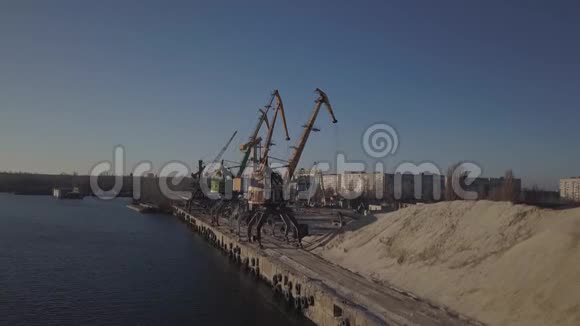 码头附近岸边的大型港口起重机用河沙和一大堆废物装载卡车一列火车视频的预览图