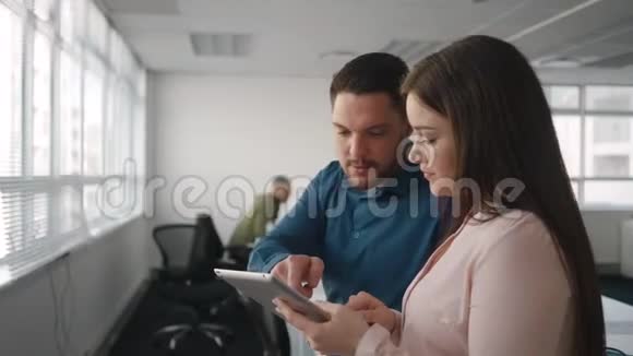 一位年轻的职业商人和女商人讨论如何在现代平板电脑上合作视频的预览图