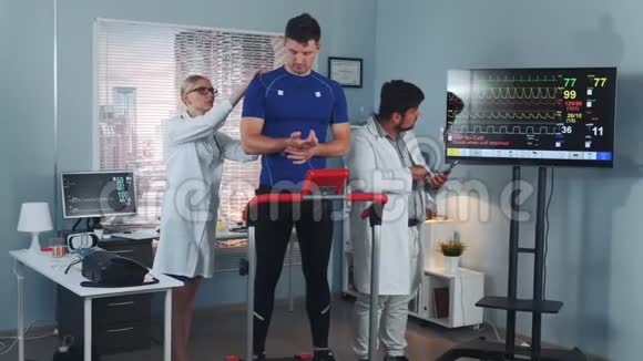 运动医学女人和男人在现代实验室对强壮的运动员采取措施视频的预览图
