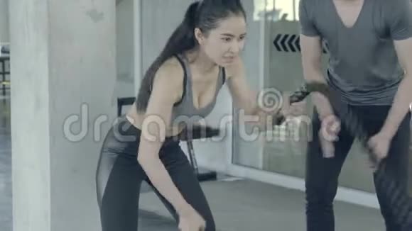 年轻的亚洲女人在健身房做战绳锻炼亚洲女孩在健身与教练视频的预览图