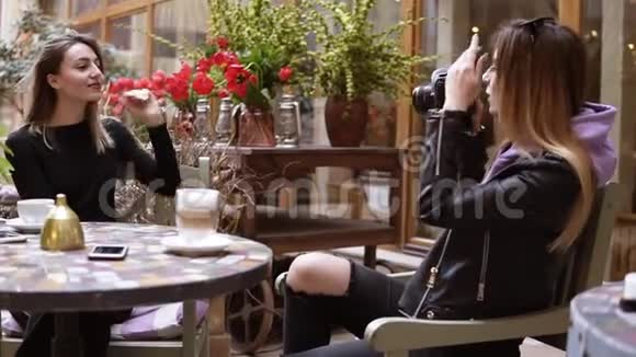 两个女孩在咖啡厅喝咖啡为记忆做一些照片一位长发女子为她的朋友拍照视频的预览图