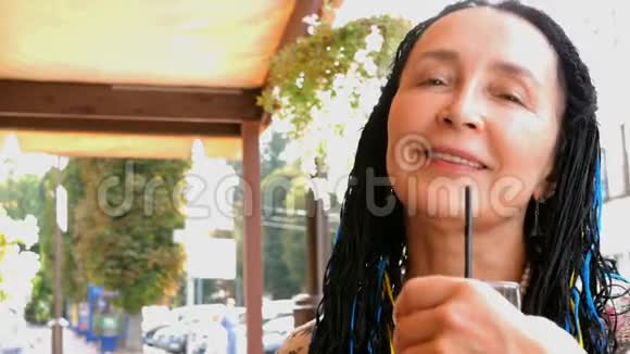 令人印象深刻的高白种人黑发女人止渴喝一杯吸管而站在一条城市街道视频的预览图