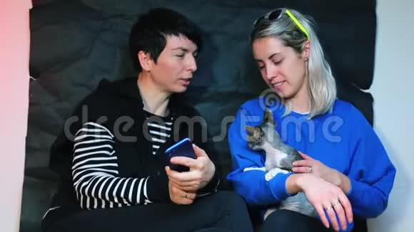 两个女孩和一只猫在聚会上女孩在智能手机上拍照视频的预览图