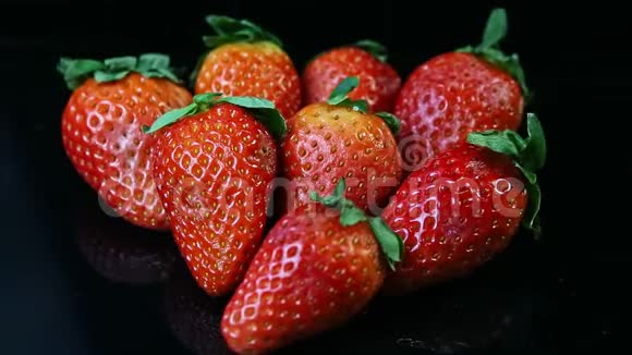 把焦点从一组新鲜多汁的红色草莓放在黑色的背景上视频的预览图