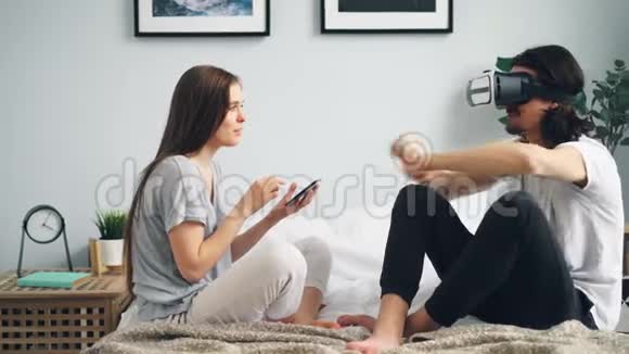 大胡子男在家里睡觉时戴着ar眼镜而女孩子摸着平板电脑视频的预览图