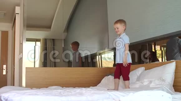 一个勇敢的小男孩在家里的床上蹦蹦跳跳慢动作视频的预览图