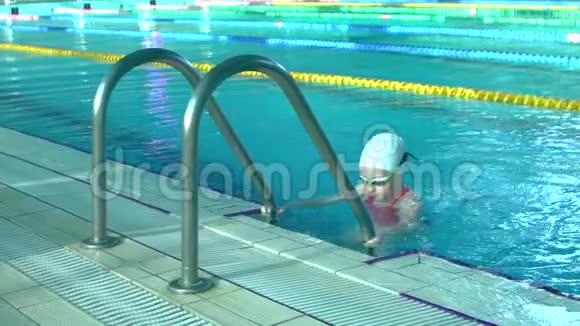 侧景年轻女子游泳从室内游泳池出来带着蓝色的水慢动作视频的预览图