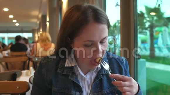 一个穿着牛仔夹克的女人在餐馆吃饭她拿着刀叉视频的预览图