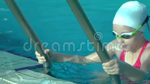 侧景年轻女子游泳从室内游泳池出来带蓝色的水慢动作视频的预览图