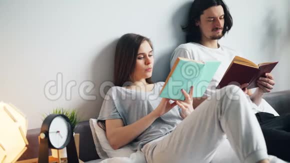 穿着睡衣的男人和女人在床上看书在家翻页视频的预览图