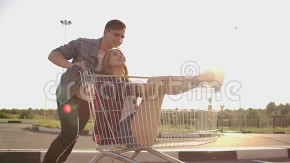 一个男人跑着推着一辆超市的手推车把一个女孩压在里面疯狂地取笑学生视频的预览图