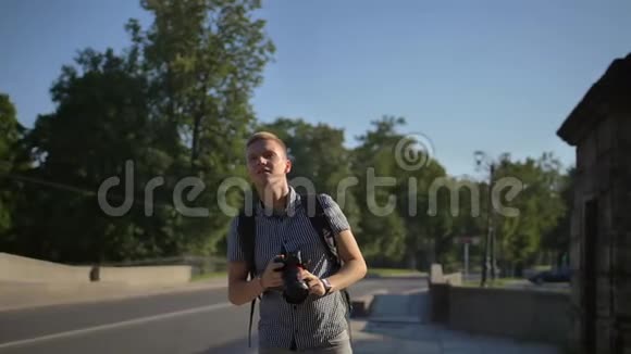 一位游客站在路边寻找拍摄好镜头的好角度视频的预览图