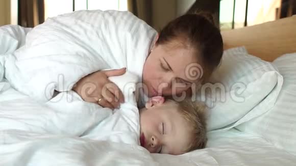 一位体贴的母亲早上在床上叫醒她熟睡的儿子视频的预览图