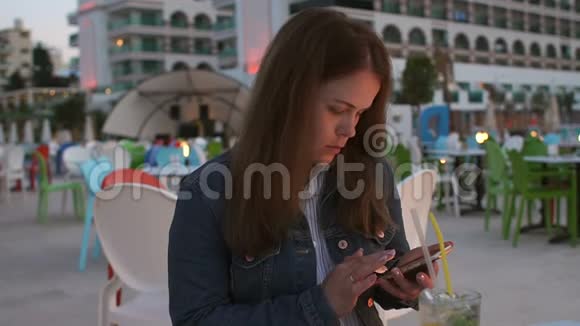 一位年轻女子的特写镜头手里拿着一部手机躺在酒店的一家咖啡馆里视频的预览图
