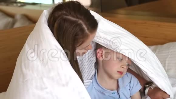 一个悲伤的婴儿在床上的肖像妈妈拥抱和安慰孩子慢动作视频的预览图