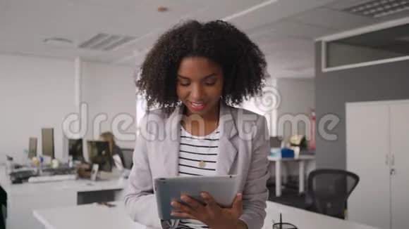 一幅有思想的微笑成功的年轻女商人使用平板电脑和她的团队在办公桌前工作的肖像视频的预览图