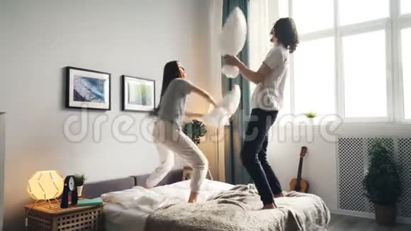 男人和女人玩枕头打架然后在床上接吻的肖像视频的预览图