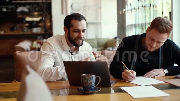 两位愉快的商人在舒适的咖啡馆里讨论项目的肖像视频的预览图