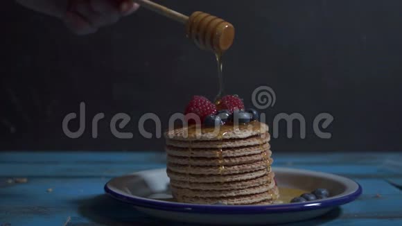 荷兰华夫饼加蜂蜜流过一叠薄煎饼在蓝色木桌上的华夫饼上滴着蜂蜜视频的预览图