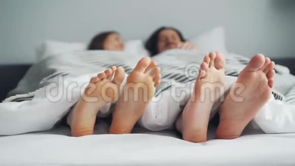 曼斯和女人的双脚在床上在毯子下随着节奏跳舞视频的预览图