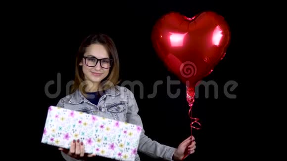 一个年轻的女孩站着拿着礼物和心形气球一个女人手里拿着礼物和氦气球视频的预览图