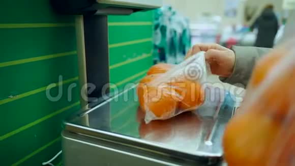 超市里的一个女人把橘子放在秤上称重视频的预览图