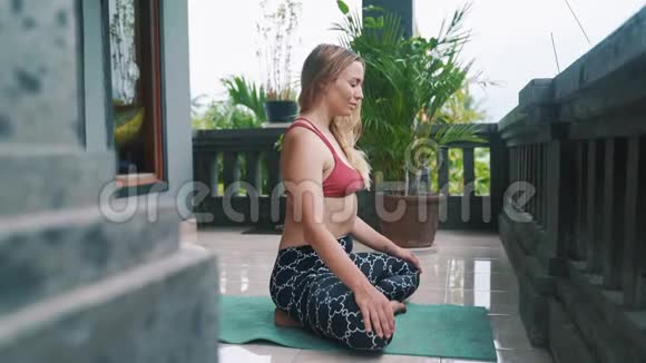 年轻女子在阳台上做瑜伽练习冥想和祈祷视频的预览图