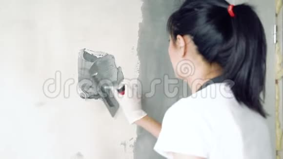 女工人在公寓或房子里用铲子粉刷墙壁把注意力集中在手上视频的预览图