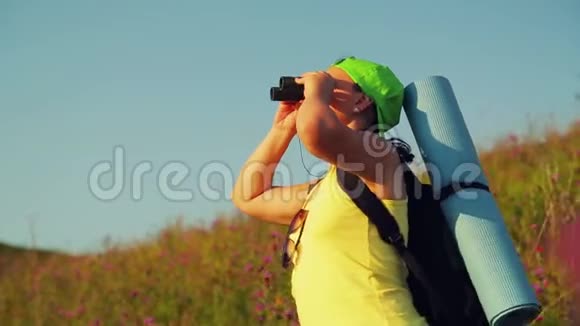 女徒步旅行者在一座小山上背着一个背包用望远镜看风景视频的预览图